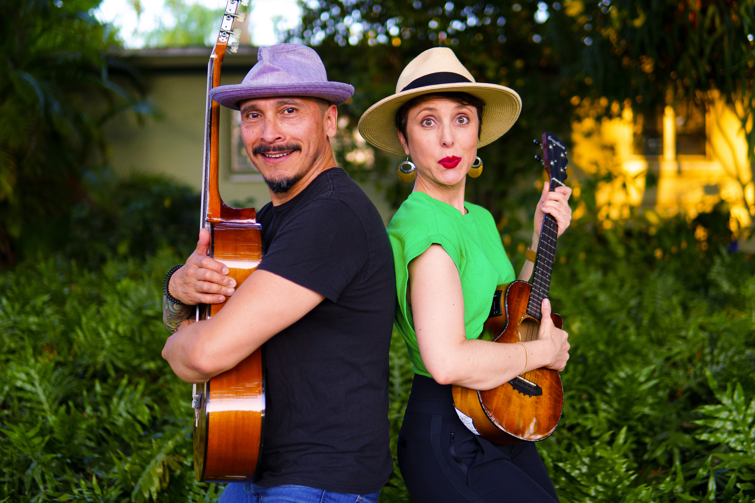 Alina in green shirt and hat and Hamlet in blue t-shirt and hat holding guitars