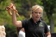 A blonde woman in a black shirt holding a snake