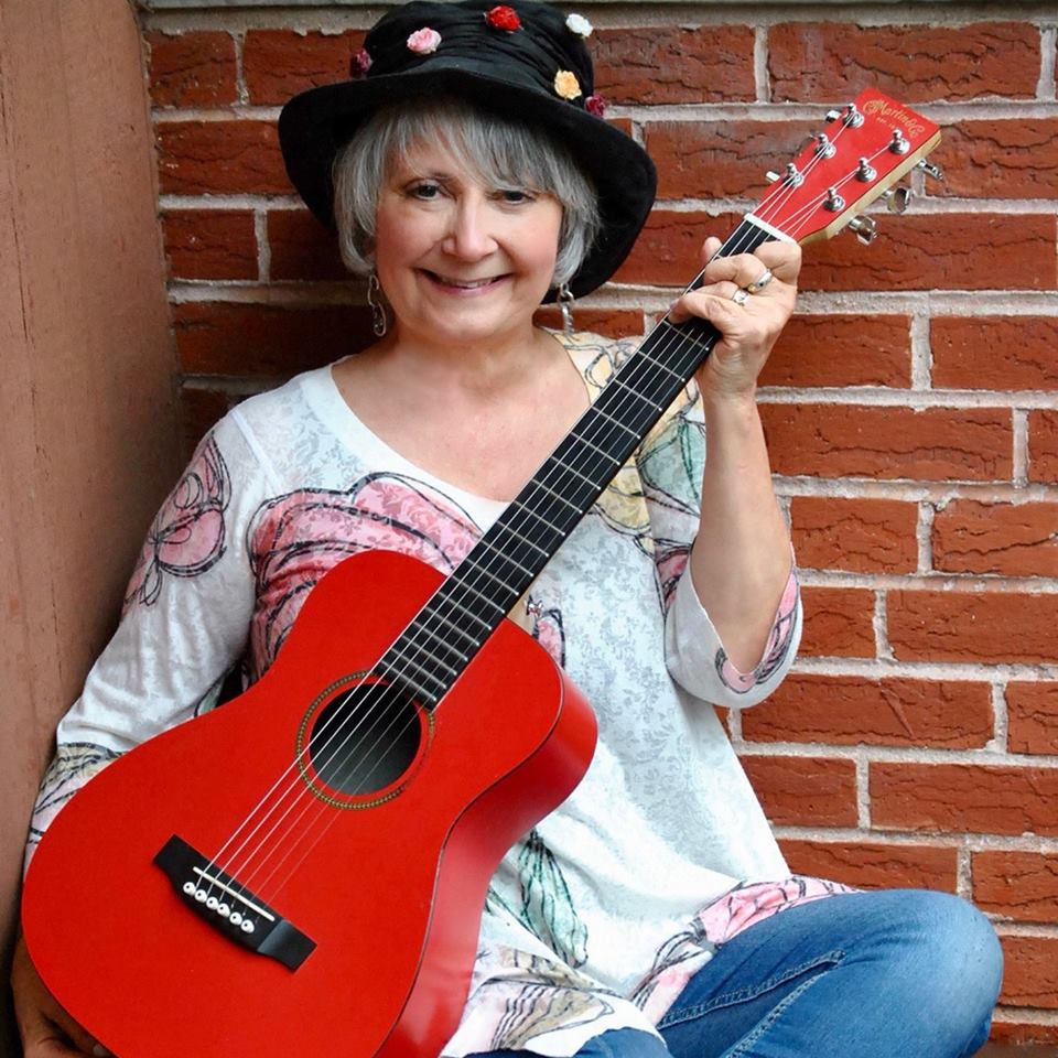 Jodi in black hat holding red guitar