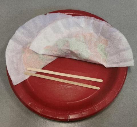 paper dumplings on a red plate with chopsticks