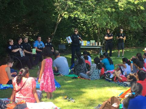 police officers reading stories to families sitting on the lawn.