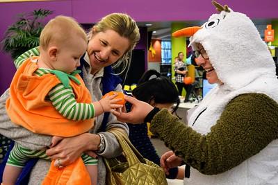 Toddler receiving pumpkin from librarian at Trick-or-Reading event