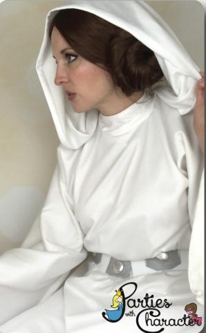 Woman with brown hair in a bun wearing a white hooded dress with a silver belt