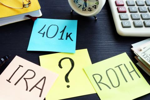 Colorful sticky notes on desk with "IRA," "401k," "Roth," and "?"