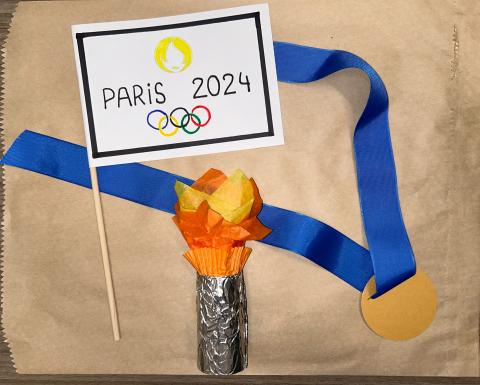 Gold medal, Paris Olympic flag, and a tissue paper Olympic torch