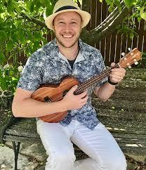 man in Hawaiian shirt and straw hat strumming a guitar