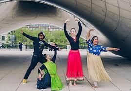 4 dancers in traditional Indian costumes under the Chicago Bean sculpture