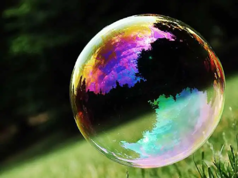 Large bubble floats over grassy field