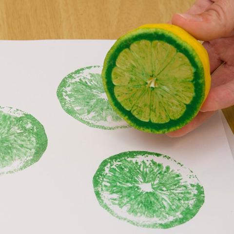 Using green paint on a lemon and stamping it on white paper