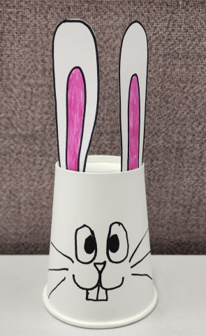 White cup with long ears glued to top and bunny face drawn on the outside.