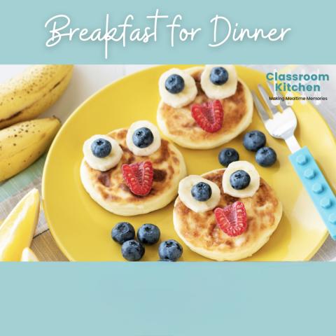 3 pancakes on a plate covered with bananas, blueberries and strawberries in the shape of a smiley face
