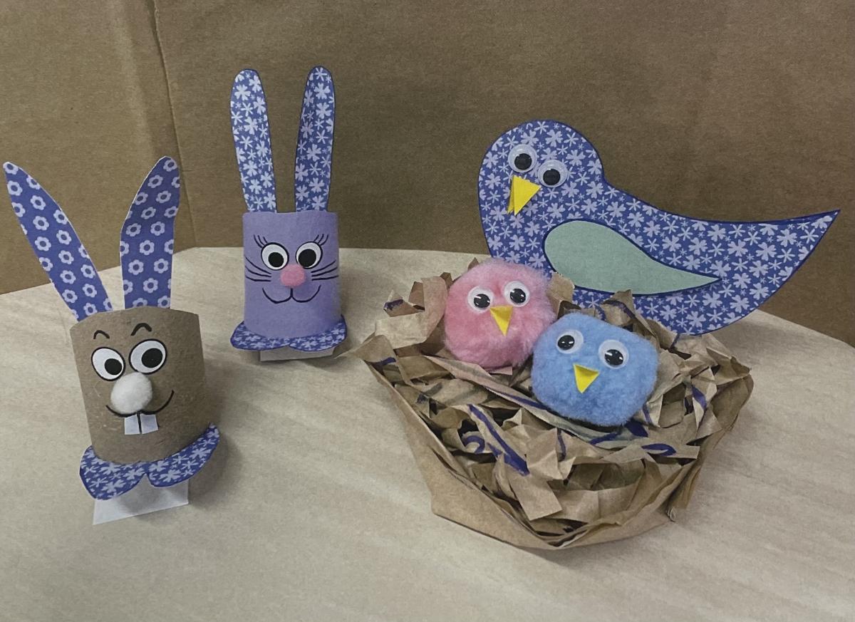 Paper birds in a nest next to paper bunnies