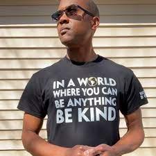 Man in sunglasses and black t-shirt against a brick wall.