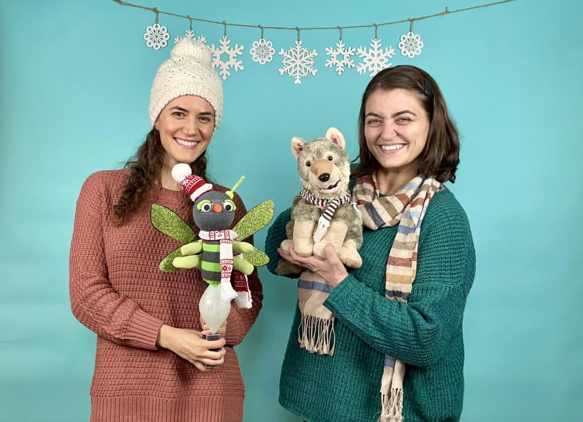 2 women in sweaters, hats and scarf with fox and firefly puppet