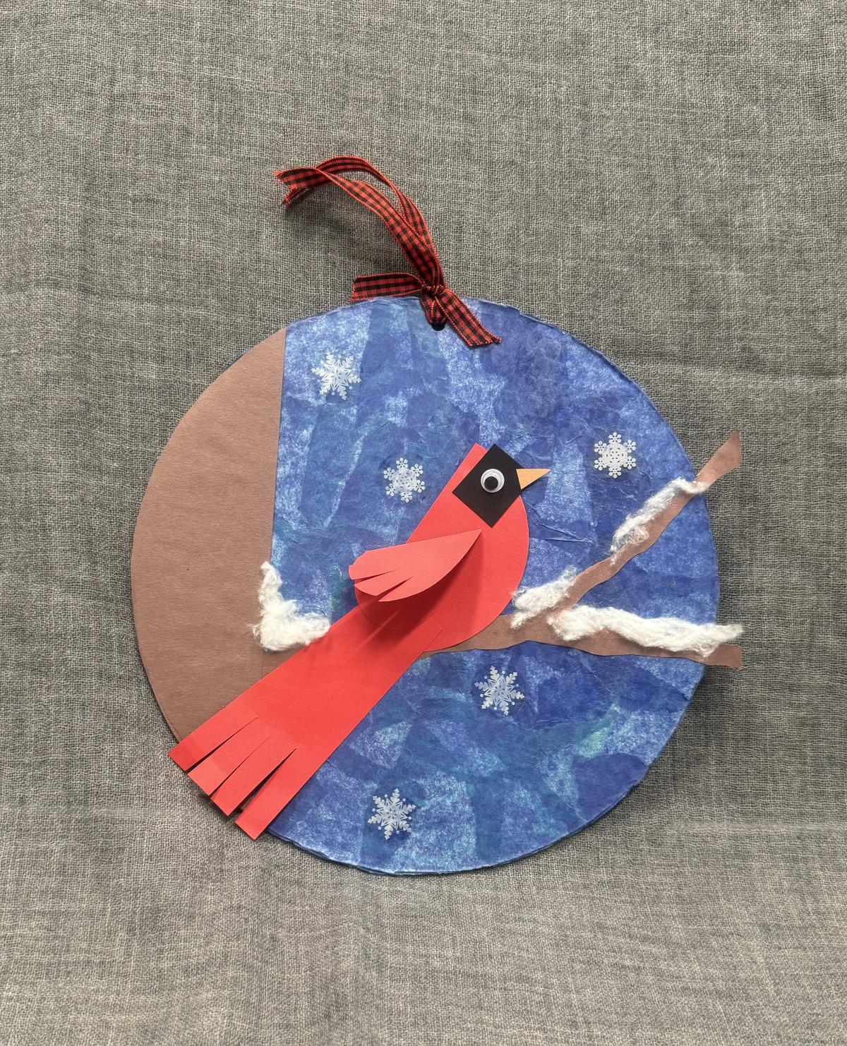 Wall hanging of a cardinal on a branch with a blue background